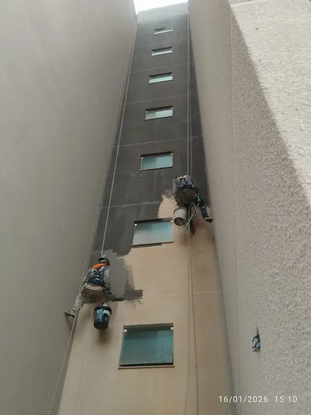 Profissional em acesso por corda limpando a fachada